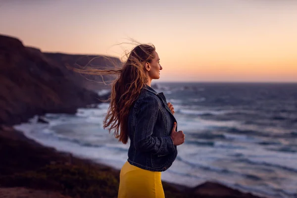 彼女の髪の風と夕日のビーチで女性 — ストック写真