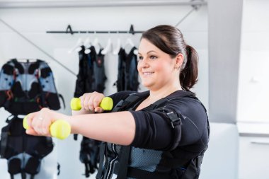 Spor salonunda ağırlıklarla spor yapan koca bir kadın.