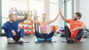 Spor salonundaki bir grup fit arkadaş motivasyon için beşlik çakıyor.