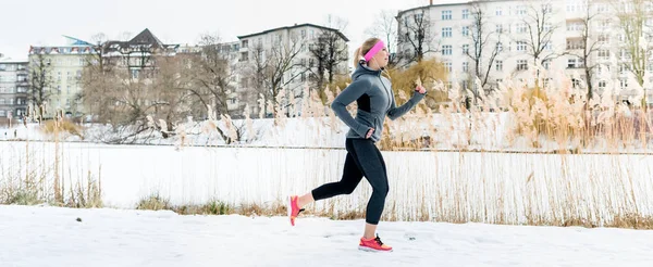 Mujer corriendo por deporte frente a edificios de apartamentos en el día de invierno — Foto de Stock