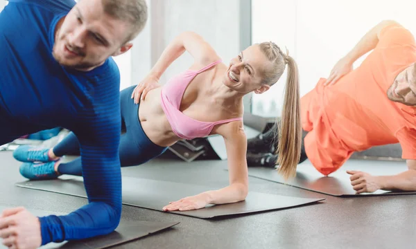 Mujer fitness y hombres en el club de salud haciendo una tabla lateral —  Fotos de Stock