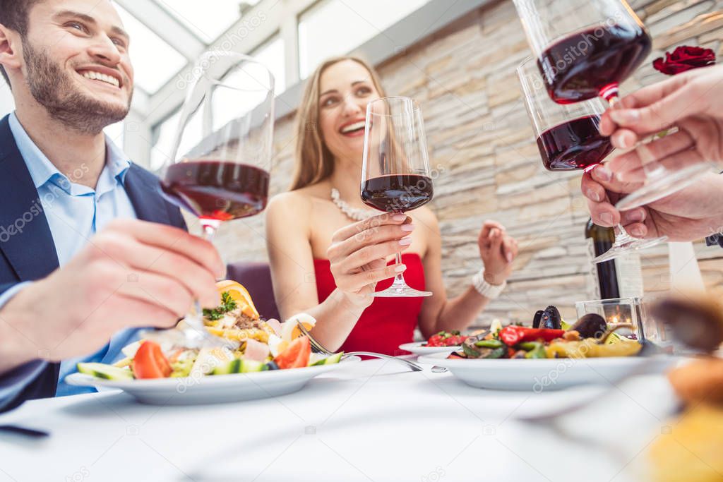 Friends in a fancy restaurant toasting with Italian red wine