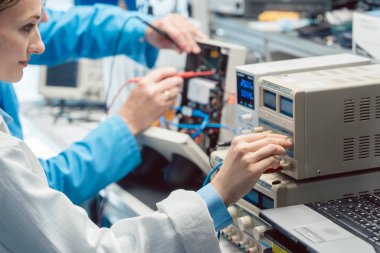 Test bankında iki elektronik mühendisi yeni bir ürünü ölçüyor.