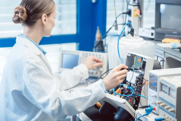 Mühendis kadın test bankında elektronik ürünü ölçüyor. — Stok fotoğraf