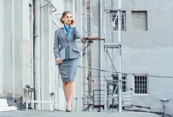 Geschäftsfrau benutzt ihr Telefon in einem industriellen Umfeld — Stockfoto