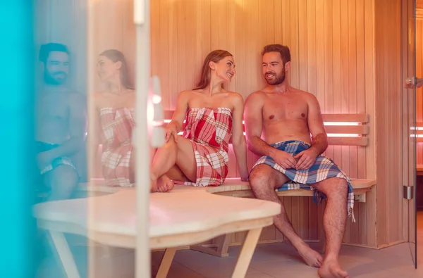 Mujer y hombre sentados lado a lado en el calor de la sauna — Foto de Stock