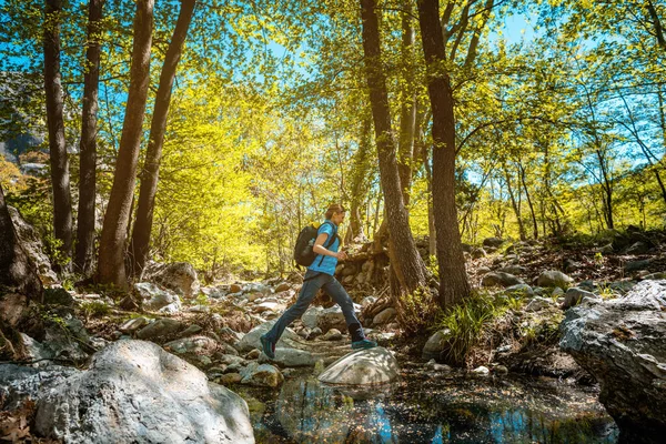 Woman hiking jumping over a creek in spring — 스톡 사진