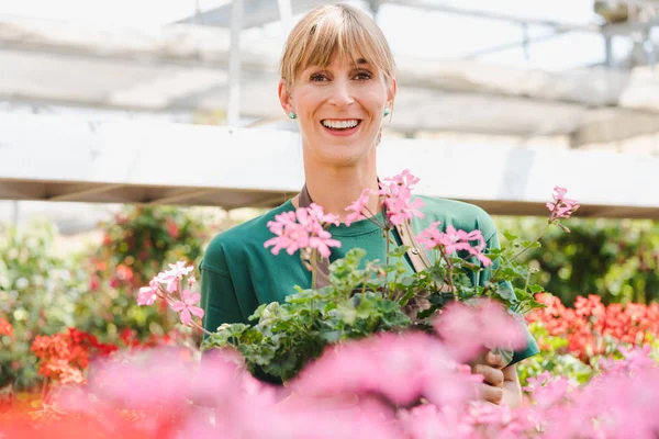 Mujer jardinero en su invernadero con flores en venta — Foto de Stock