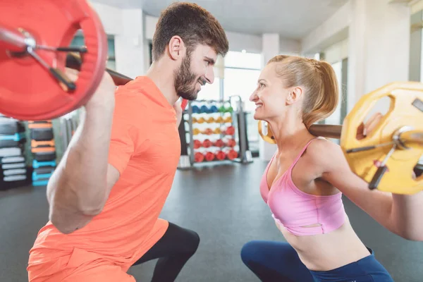 Pareja de mujer y hombre en el gimnasio con pesas en competición — Foto de Stock