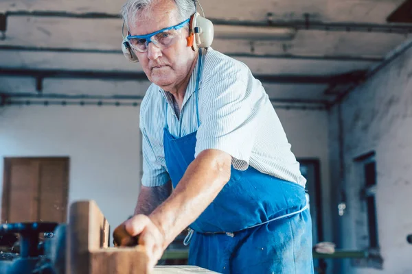 Carpintero senior trabajando con cepilladora de madera en pieza de trabajo — Foto de Stock