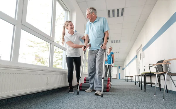 Anziani in riabilitazione imparare a camminare con le stampelle — Foto Stock