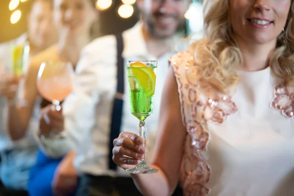 Persone che tengono cocktail colorati in un bar — Foto Stock