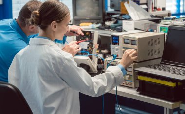Test bankında iki elektronik mühendisi yeni bir ürünü ölçüyor.
