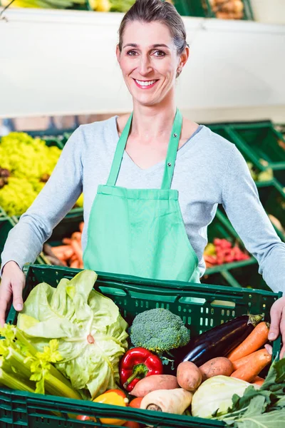 Verkoopster bewaardoos met biologische groenten in de winkel — Stockfoto