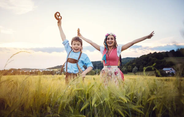 Mãe e filho felizes na Baviera saltando em um prado — Fotografia de Stock