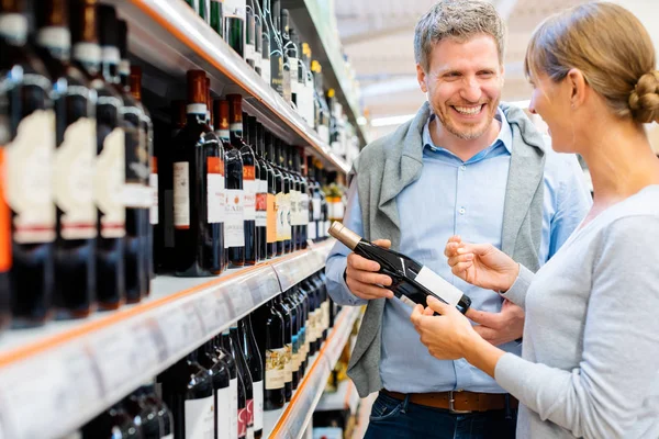 Kvinna och man att köpa vin i stormarknad — Stockfoto