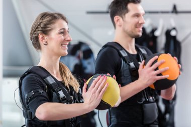 Fit woman and man with ball in wireless ems exercise gym