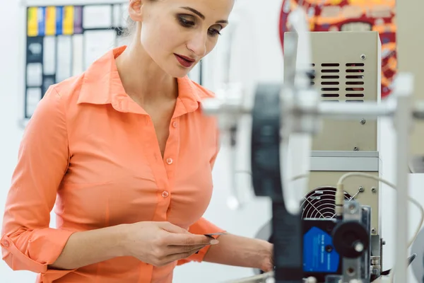 Worker checking textile label fresh from the printing machine — 스톡 사진