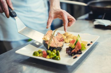Aşçı, restoranın mutfağında özenle balık tabağını bitiriyor.