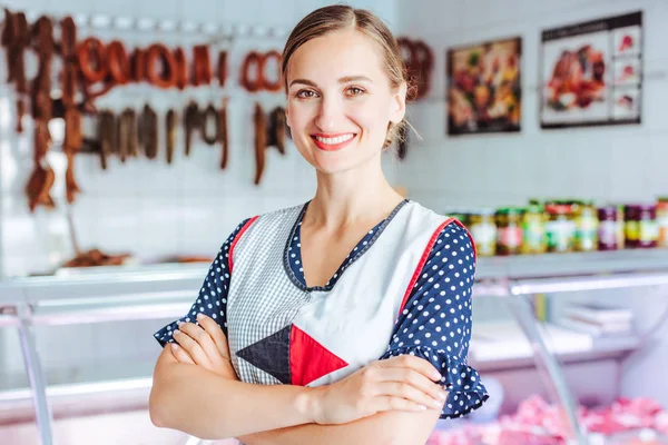 Горда жінка, що продає м'ясо та сосиски в м'ясному магазині — стокове фото