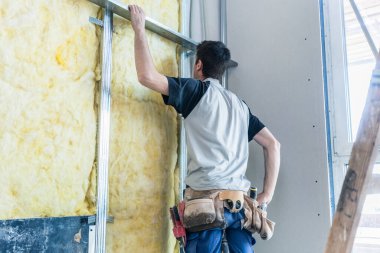 İnşaat alanındaki yeni bir binanın duvarını yalıtan işçiler