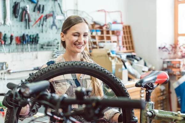 自転車の車輪を通して見る自転車整備士の女性 — ストック写真