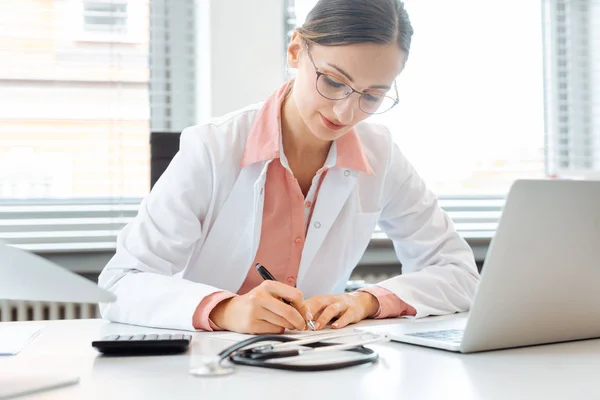 Doctor doing office works and administration on the desk in her office — Stockfoto