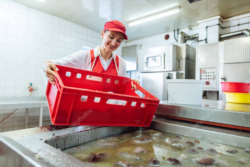 Woman working in butchery about to boil sausages in hot water