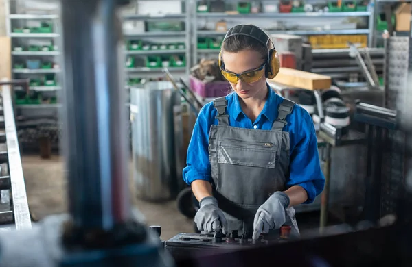 Arbeiterin, die eine Werkzeugmaschine in einer Metallwerkstatt oder Fabrik bedient — Stockfoto