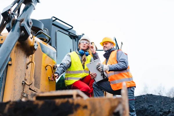 Kvinna och man arbetare i stenbrott på grävmaskin — Stockfoto