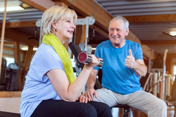 Mujer mayor en el gimnasio haciendo ejercicio con pesas para la aptitud —  Fotos de Stock