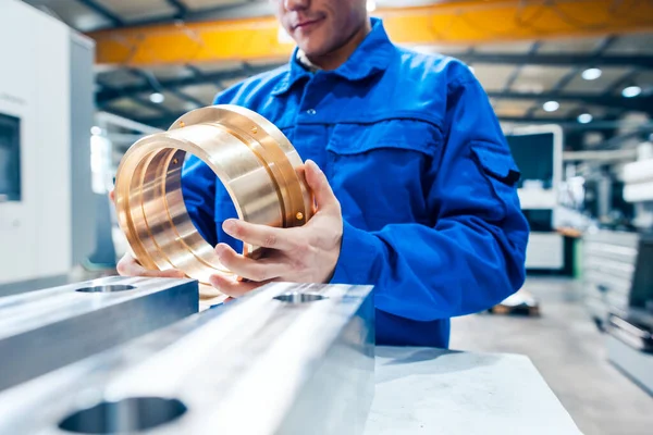 Apprentice in metalworking looking at workpiece — ストック写真