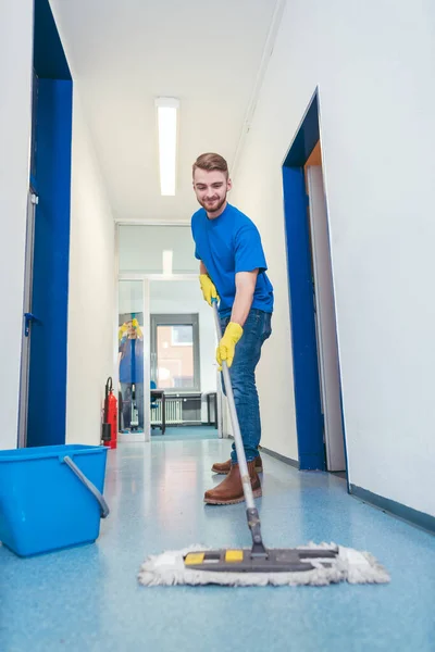 Cleaner man mopping the floor in a hall — Stock Photo, Image