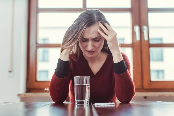 Mujer con dolor de cabeza y migraña sentada en su apartamento — Foto de Stock