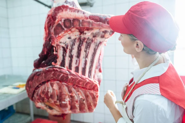 Mulher açougueiro inspecionando pedaço de carne a ser processado — Fotografia de Stock