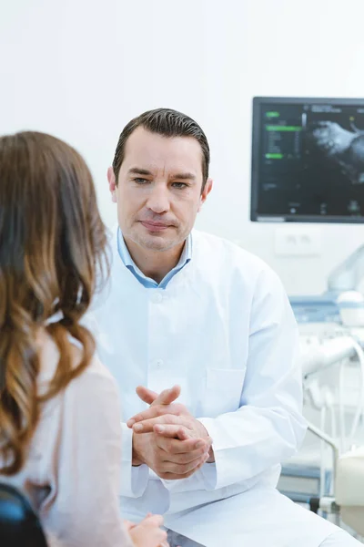 Gynecologist in his doctors office seeing a patient — 스톡 사진