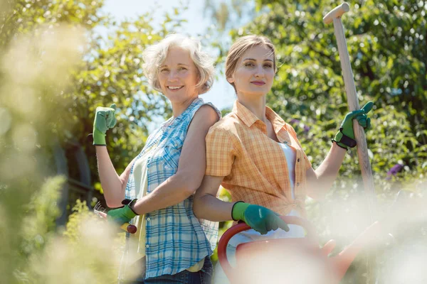 Giovane e anziana donna in posa per la foto nel loro giardino — Foto Stock