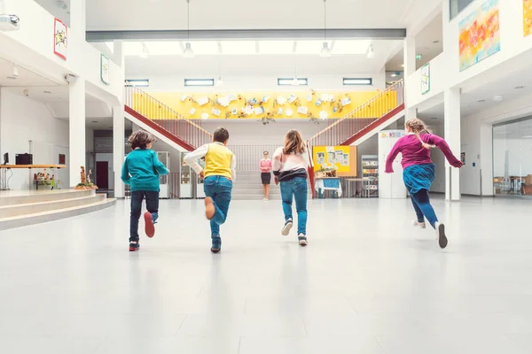 Estudiantes corriendo a sus clases en la sala principal de la escuela — Foto de Stock