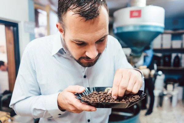 Homme aux grains de café fraîchement torréfiés — Photo