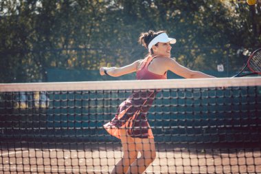 Kırmızı spor elbiseli kadın tenis oynuyor.