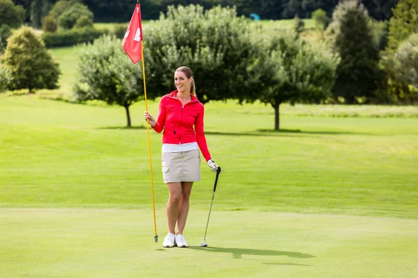 Retrato de una golfista sosteniendo bandera y club de golf —  Fotos de Stock