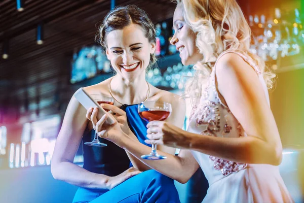 Dos mujeres en un bar mirando su teléfono móvil — Foto de Stock