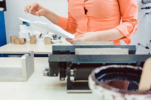 Worker checking design or a print to be run on printing machine