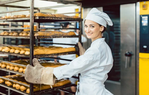 Wanita Baker mendorong lembaran dengan roti dalam oven memanggang — Stok Foto