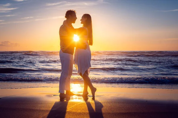 Romantisch koppel in liefde zoenen op het strand tijdens zonsondergang — Stockfoto