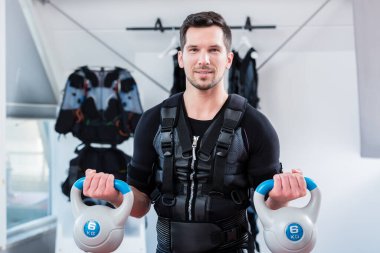 Jimnastik salonundaki güçlü adam ağırlık antrenmanı yapıyor.