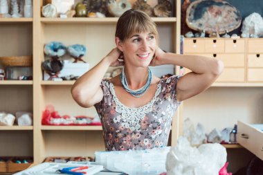 Değerli taşlardan bir kolye yapmaya çalışan bir kadın.