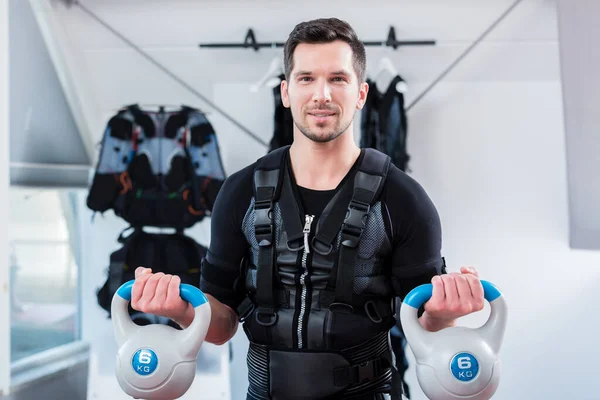 Hombre fuerte en ems gimnasio haciendo entrenamiento de fitness con pesas —  Fotos de Stock