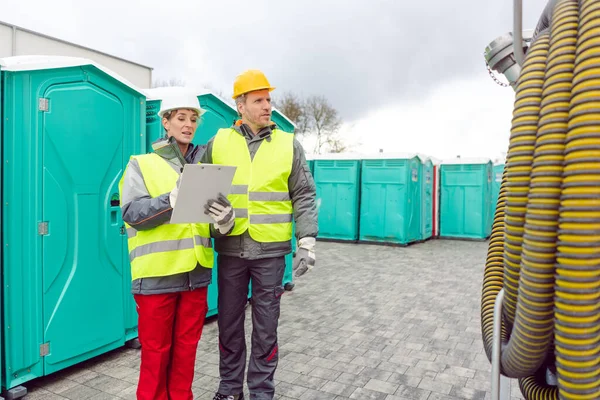 Workers inspecting mobile toilet before shipment — Stock Photo, Image