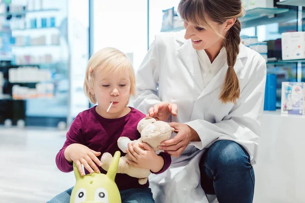 Niña pequeña en la farmacia hablando con el químico — Foto de Stock